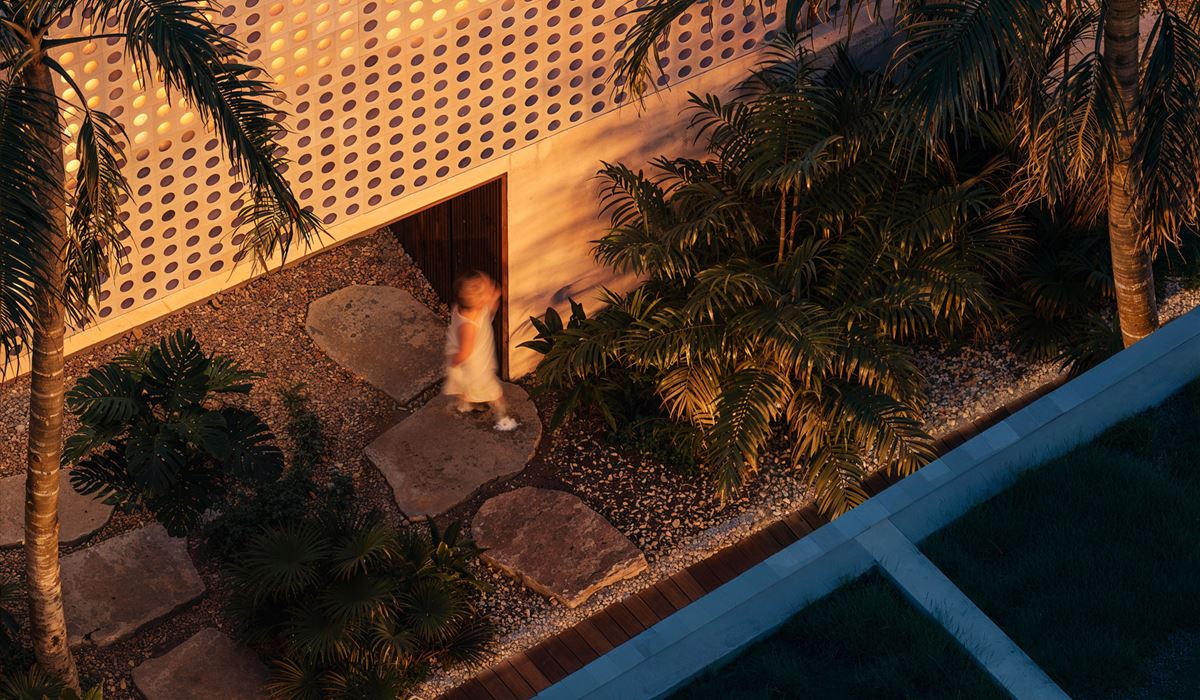The perforated facade at dusk, lit from within